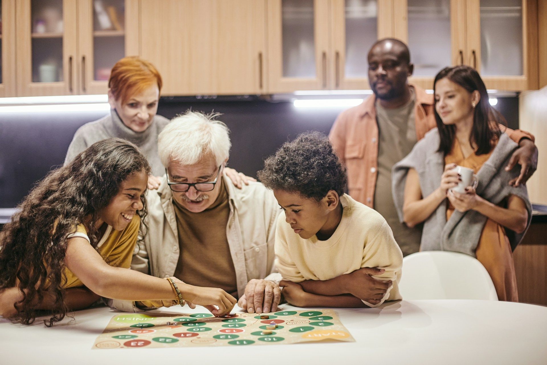 Group playing a board game at a kitchen table, focused and smiling in a cozy home setting