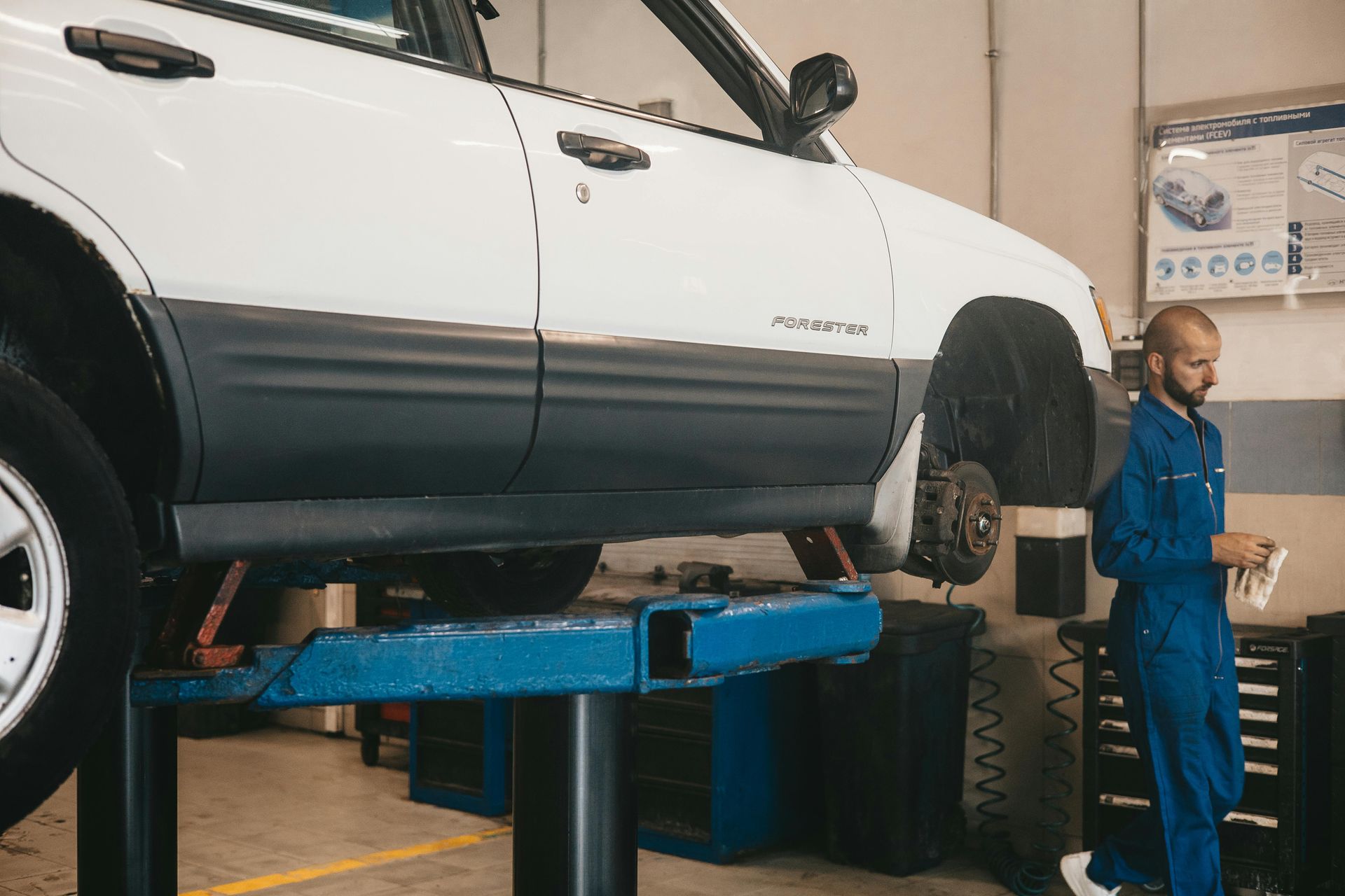 Car on a lift in an auto repair shop with a mechanic standing nearby