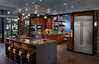 Modern kitchen with island seating, wood cabinetry, stainless appliances, and pendant lights