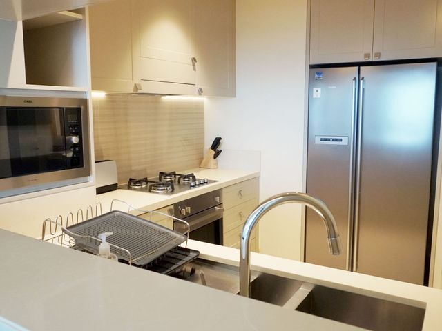 Modern kitchen with stainless steel refrigerator, gas stove, microwave, sink, and dish rack on the counter