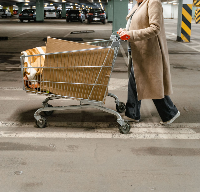 Person pushing a shopping cart with boxes in a parking garage