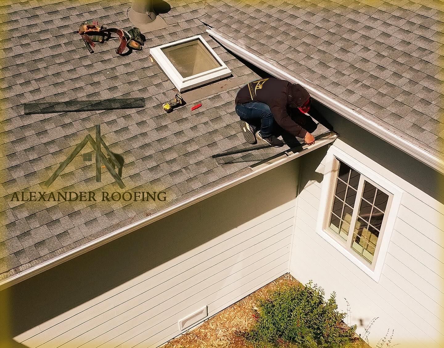 A man is working on the roof of a house sponsored by alexander roofing