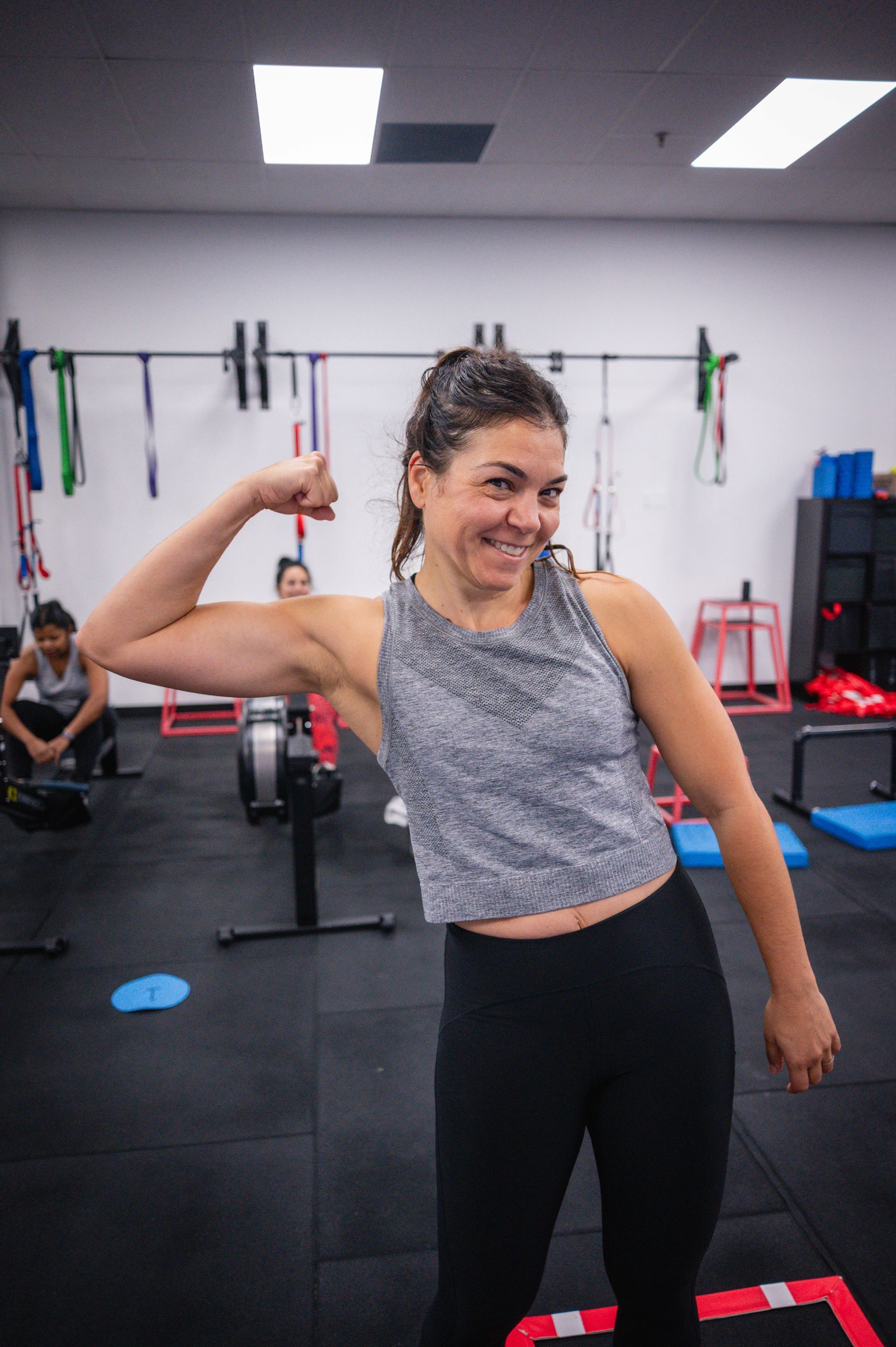 Person doing a V-up on a blue mat in Andwell Fitness, Toronto, ON gym, with weights and exercise equipment in the background