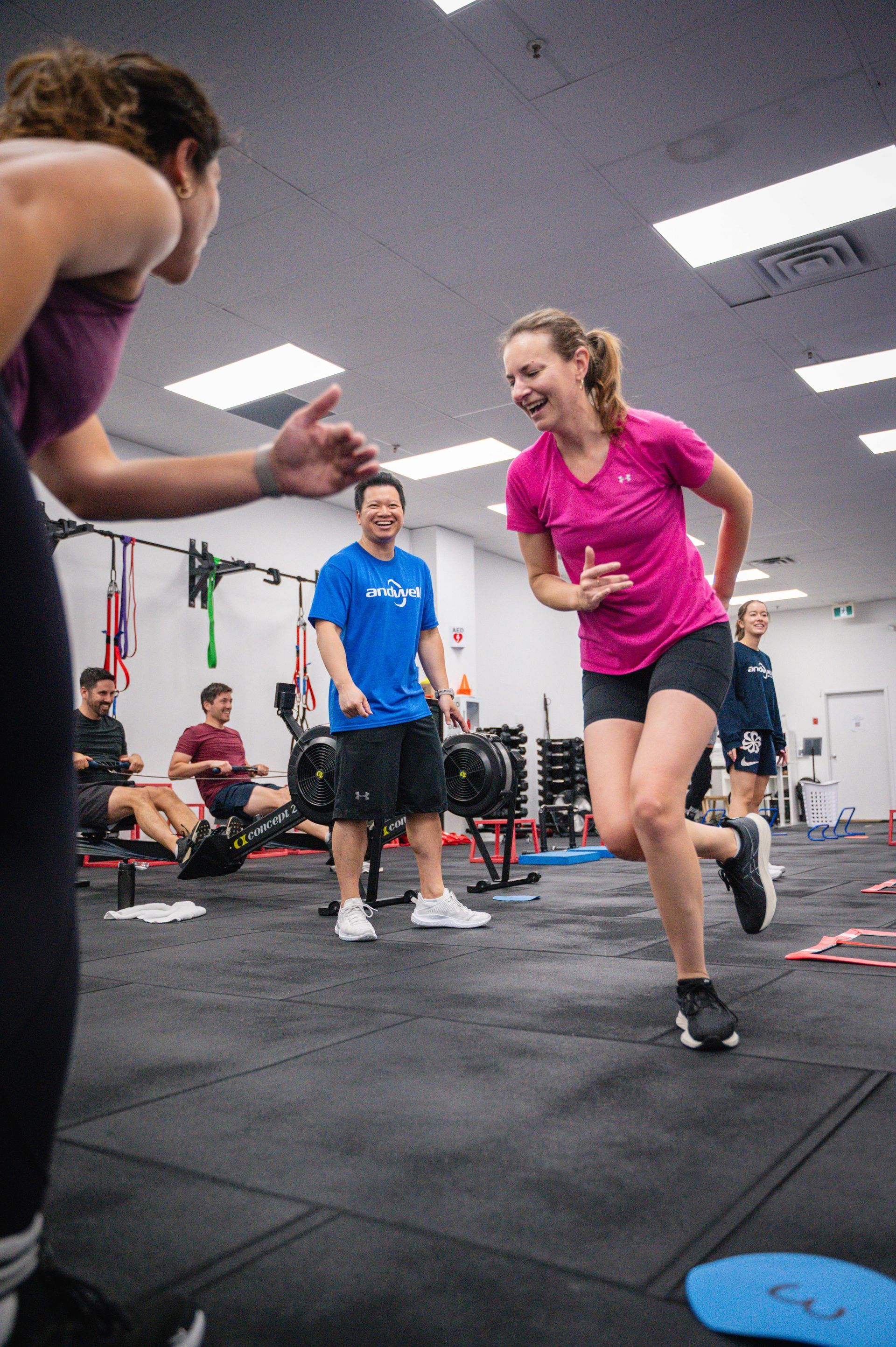 Person doing a V-up on a blue mat in Andwell Fitness, Toronto, ON gym, with weights and exercise equipment in the background