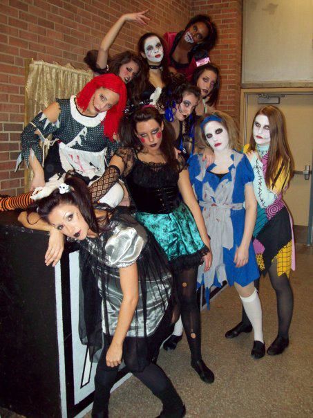 Group of costumed figures pose in front of a brick wall; zombie, fairy tale, and gothic themes are apparent.