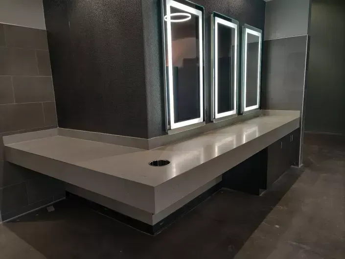 Modern restroom vanity with mirror lights and dark tiled walls