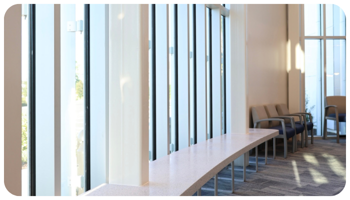Bright hallway with tall windows, a long wooden bench, and chairs along the wall