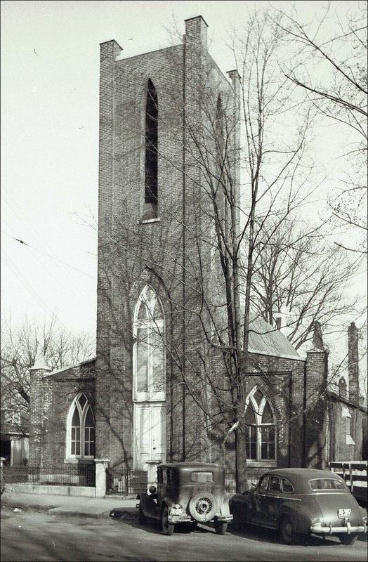 A black and white photo of a church with cars parked in front of it A black and white photo of a church with cars parked in front of it