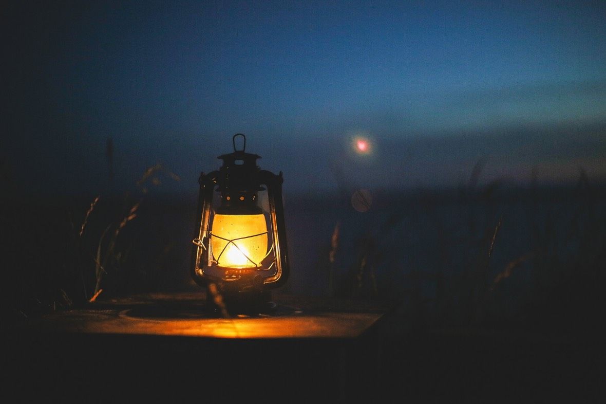 A lantern is lit up in the dark with a full moon in the background. A lantern is lit up in the dark with a full moon in the background.