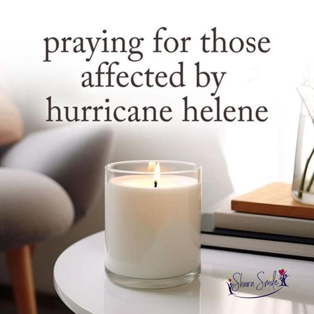 A candle on a table with the words praying for those affected by hurricane helene A candle on a table with the words praying for those affected by hurricane helene
