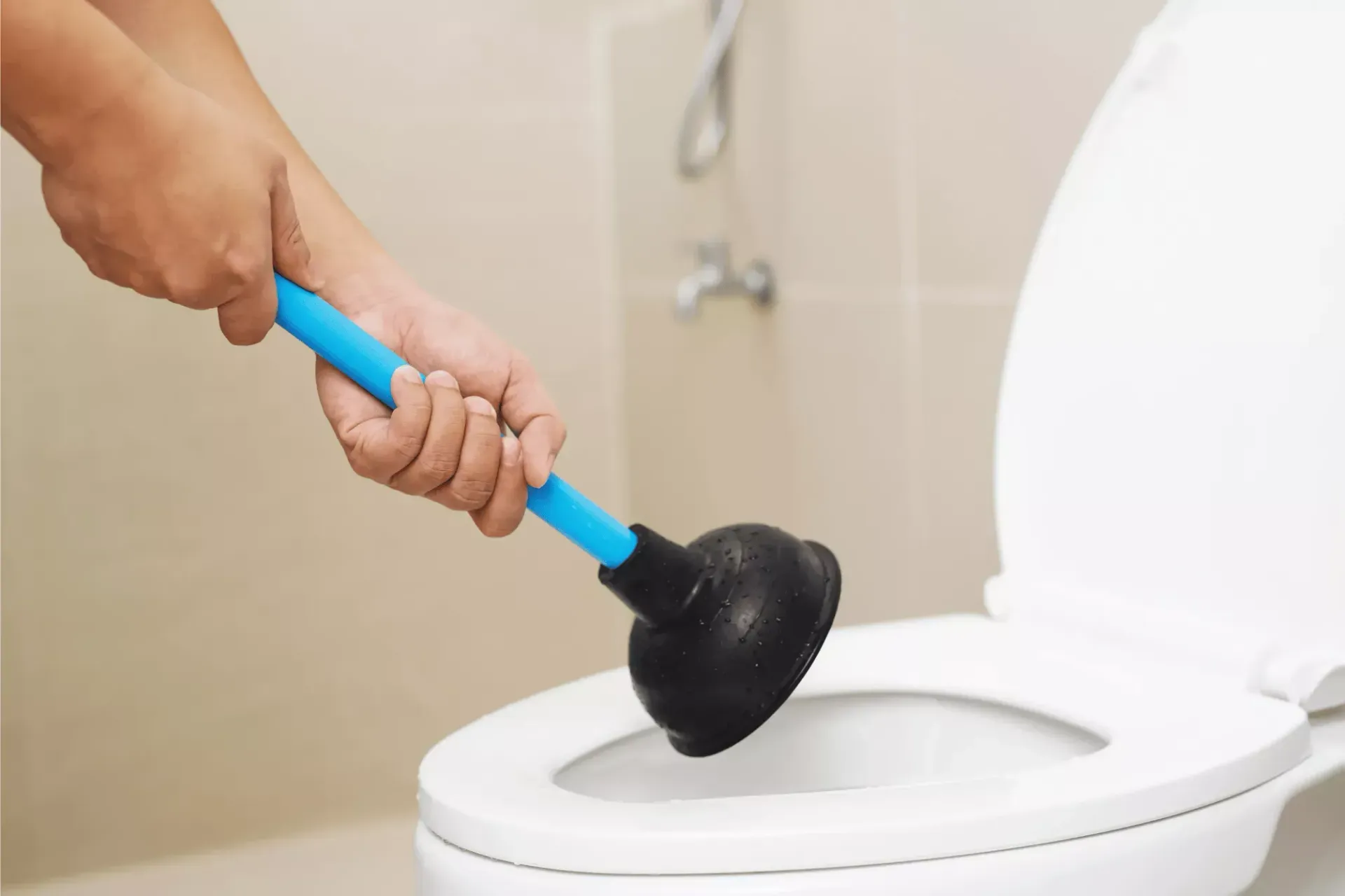 Plumber using a plunger to unclog a toilet during a toilet repair service call in Bakersfield CA