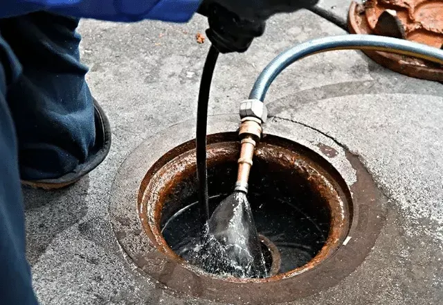 Hydro jetting hose inserted into a sewer manhole to flush and clear a clogged drain line in Bakersfield CA