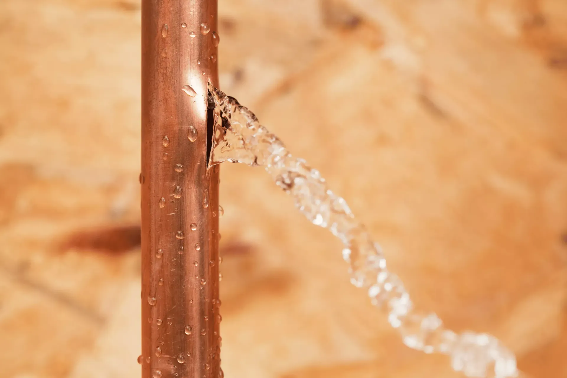 Burst copper pipe spraying water inside a wall requiring emergency plumbing repair in Bakersfield CA