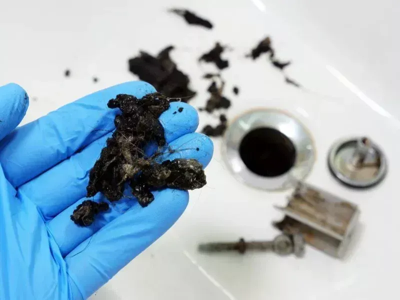 Plumber removing hair and debris from a clogged sink drain in Bakersfield CA