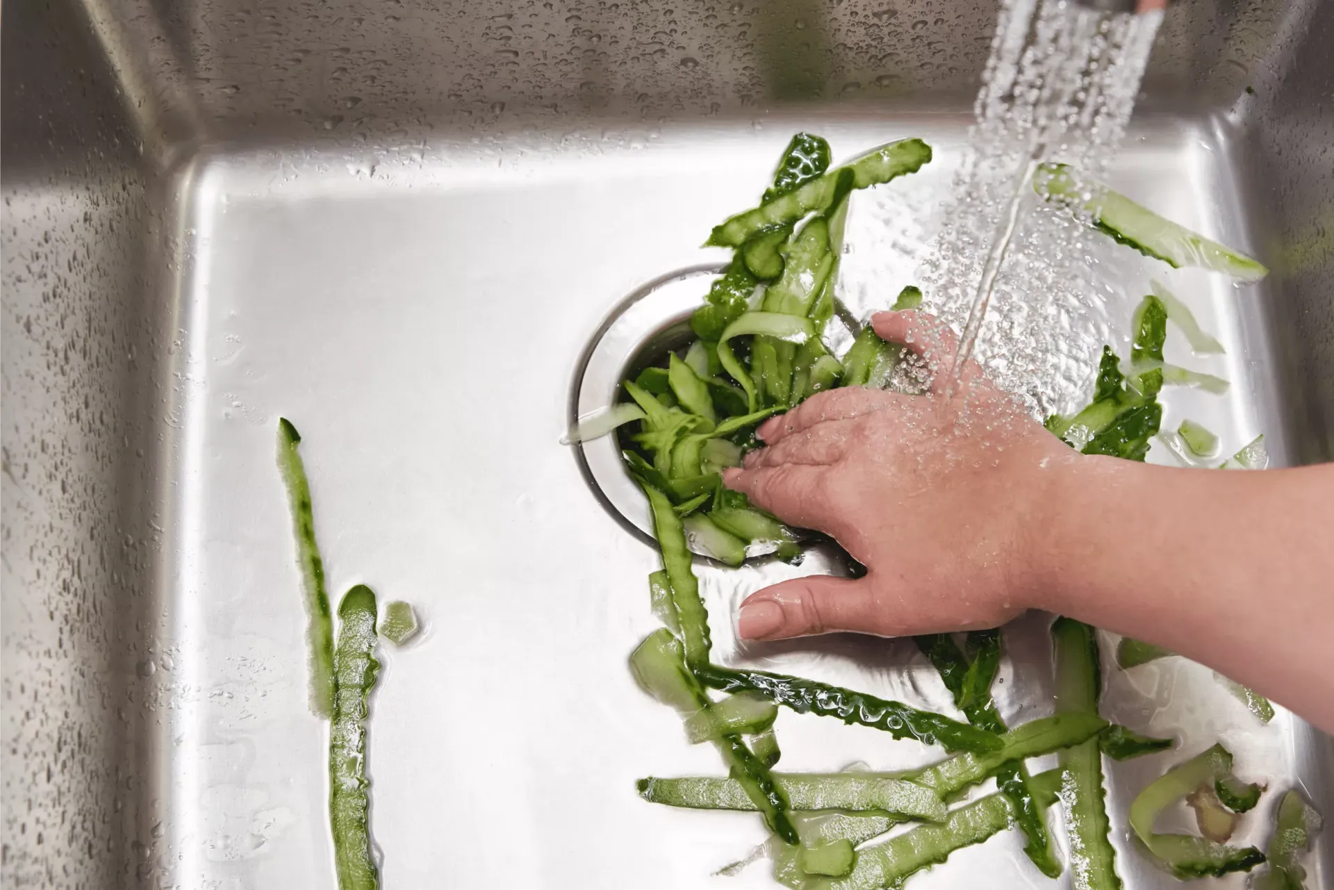 Food scraps going into a kitchen sink garbage disposal in a Bakersfield home