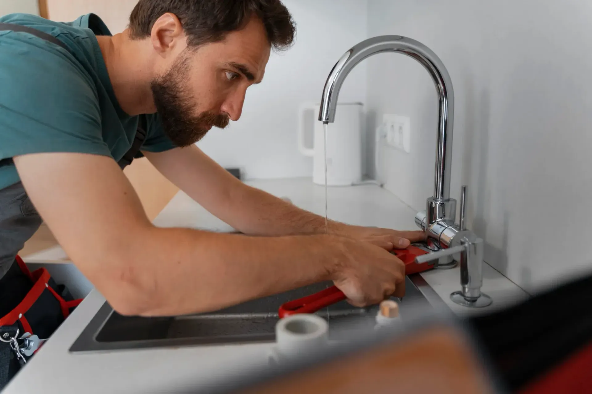 Plumber inspecting and adjusting a kitchen faucet to diagnose and fix low water pressure in a Bakersfield home