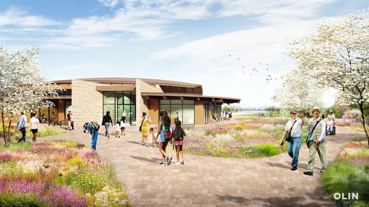 People walking on a path towards The Vista event center with a brick and wood facade, surrounded by wildflowers.