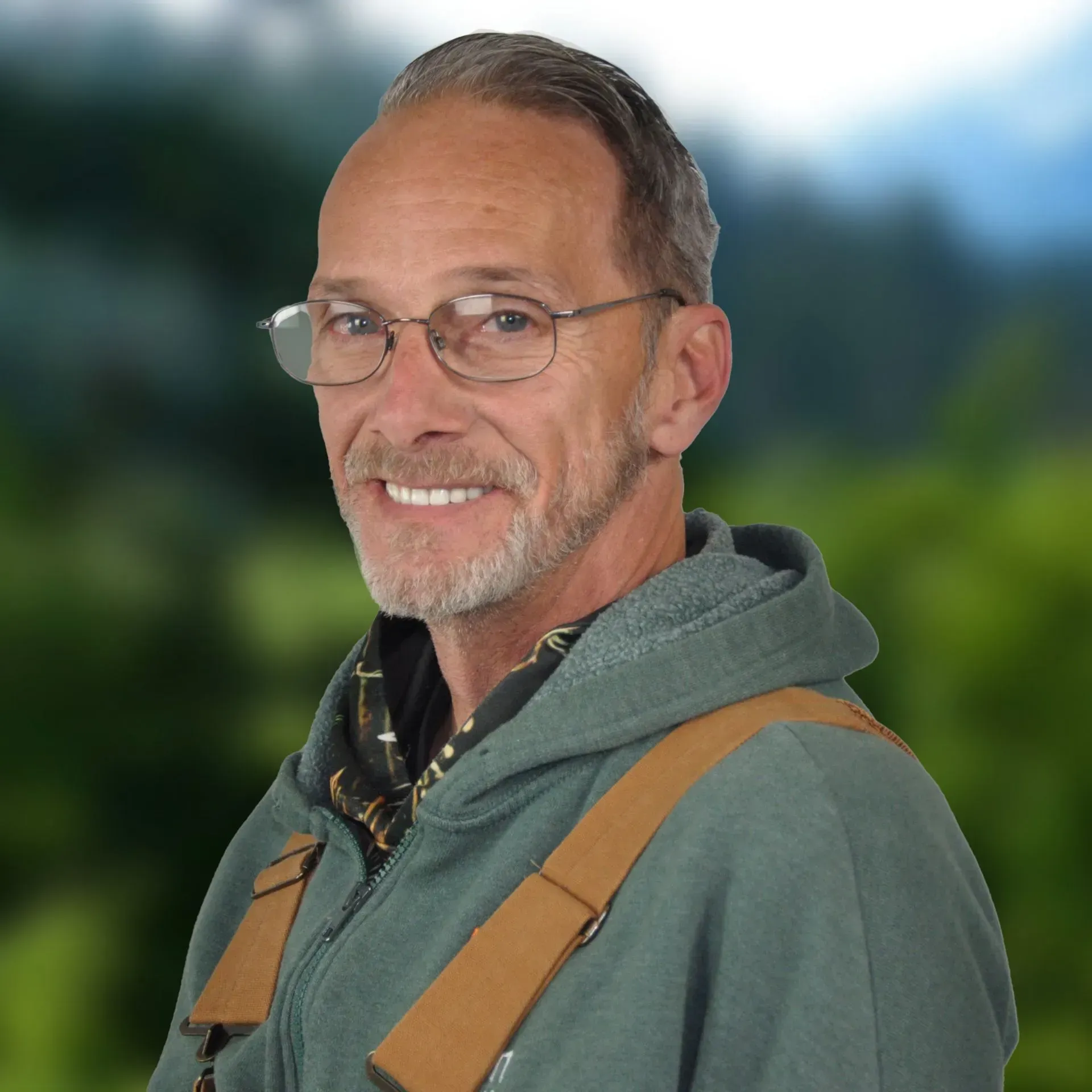 Kevin Beck in gray blazer and blue shirt smiles, with a blurred nature background.