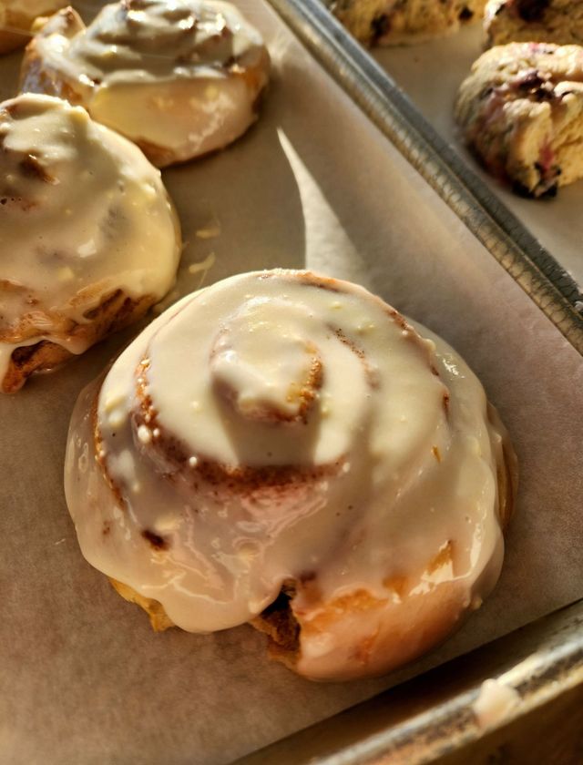 Iced cinnamon rolls on a baking tray, close-up of glazed swirls.