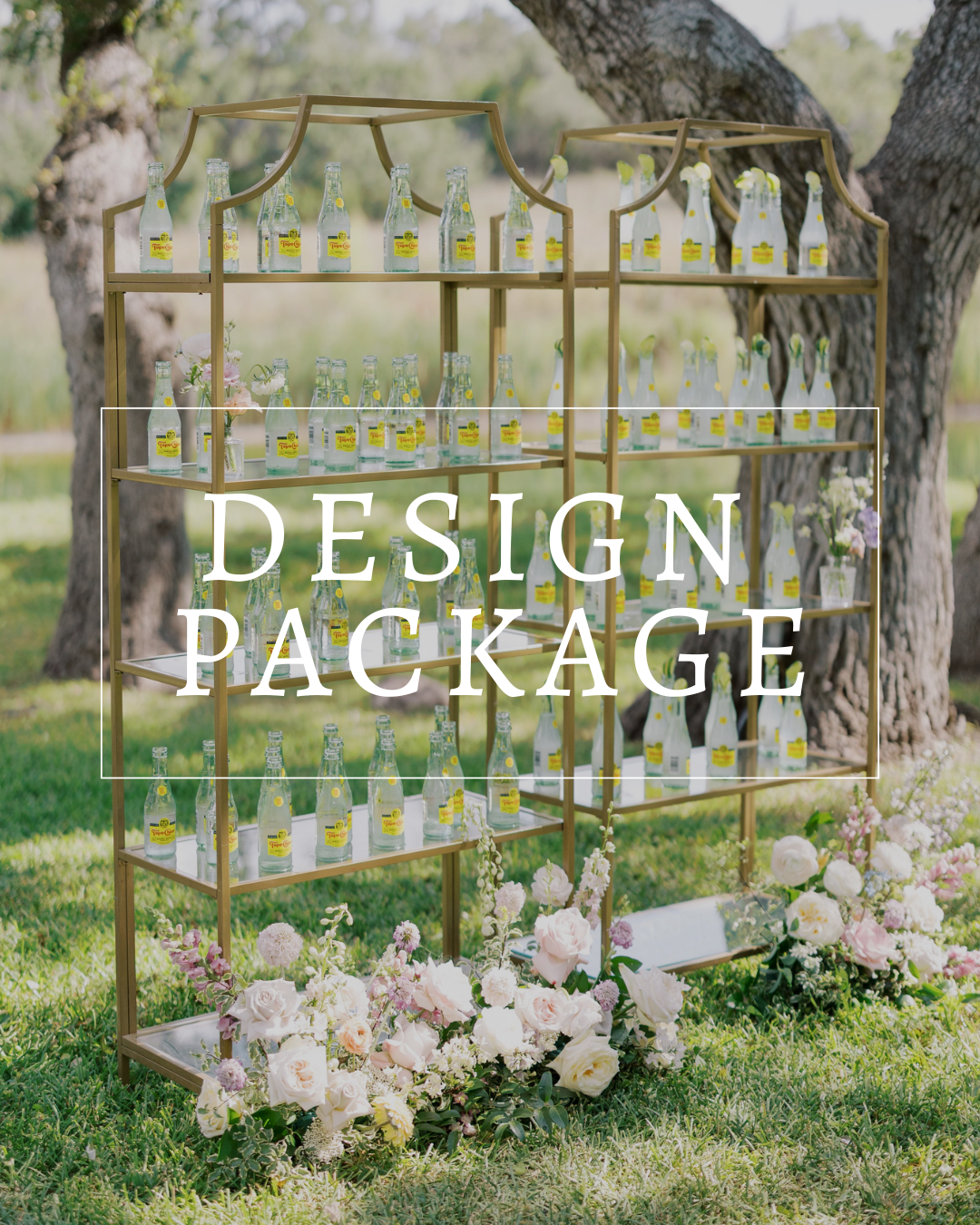A gold tiered display shelf holding bottled drinks, decorated with flowers, positioned outside beneath large trees.