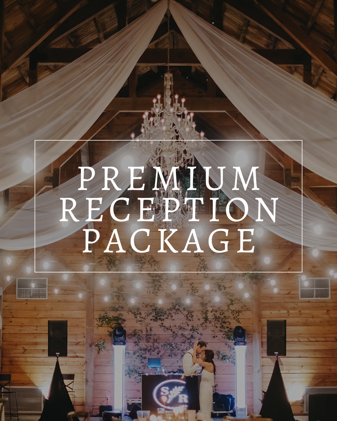 A couple dancing in a rustic, barn-style wedding venue decorated with white drapery, a large chandelier, and fairy lights.