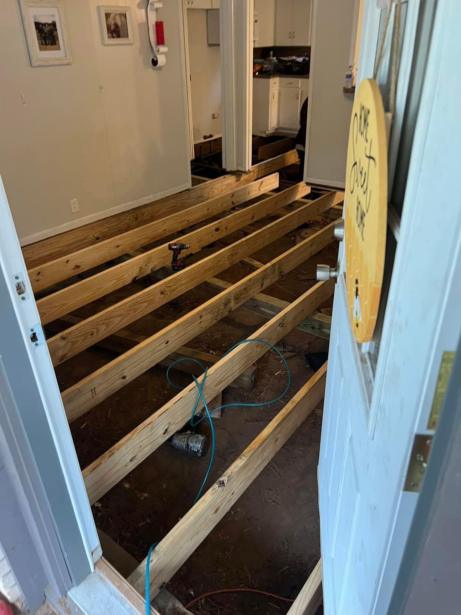 Partially demolished floor with exposed joists in a hallway doorway