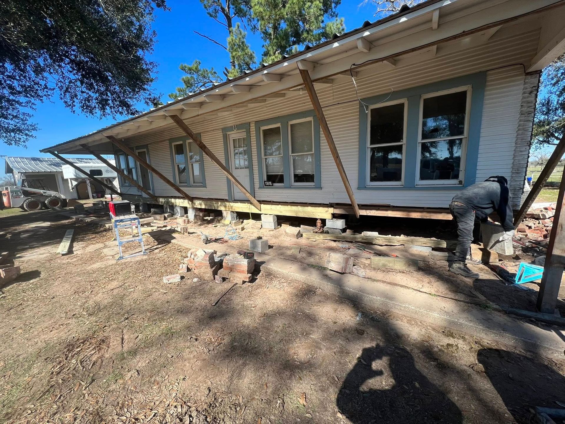 House exterior with a raised porch, exposed foundation, and dirt yard under construction