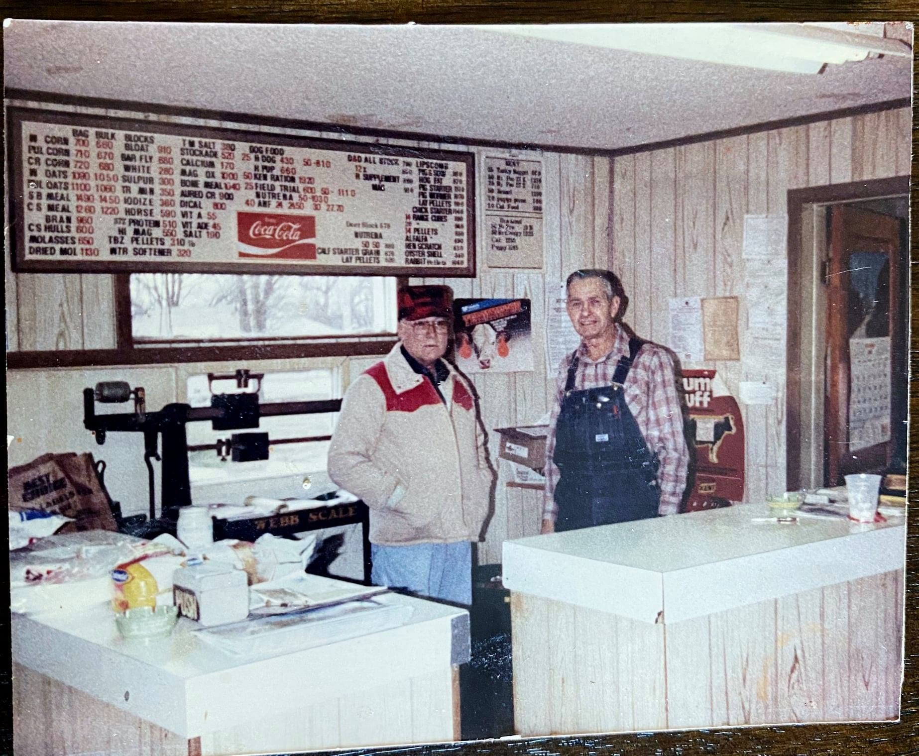 Two men standing in front of a coca cola sign