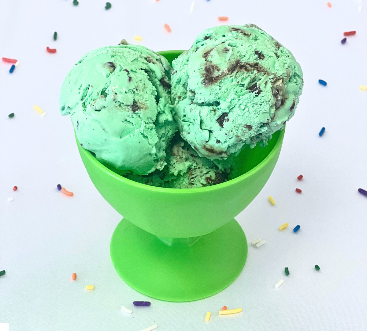 Three scoops of mint chocolate chip ice cream in a green cup