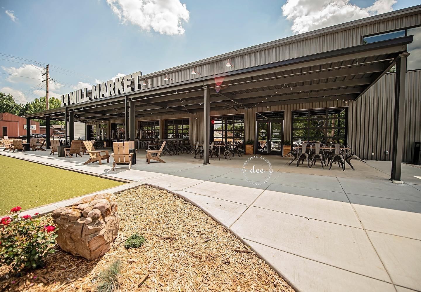 A large building with a patio and tables and chairs in front of it.