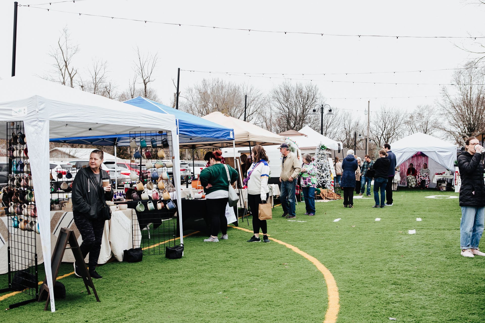 A group of people are standing in a field at a market.
