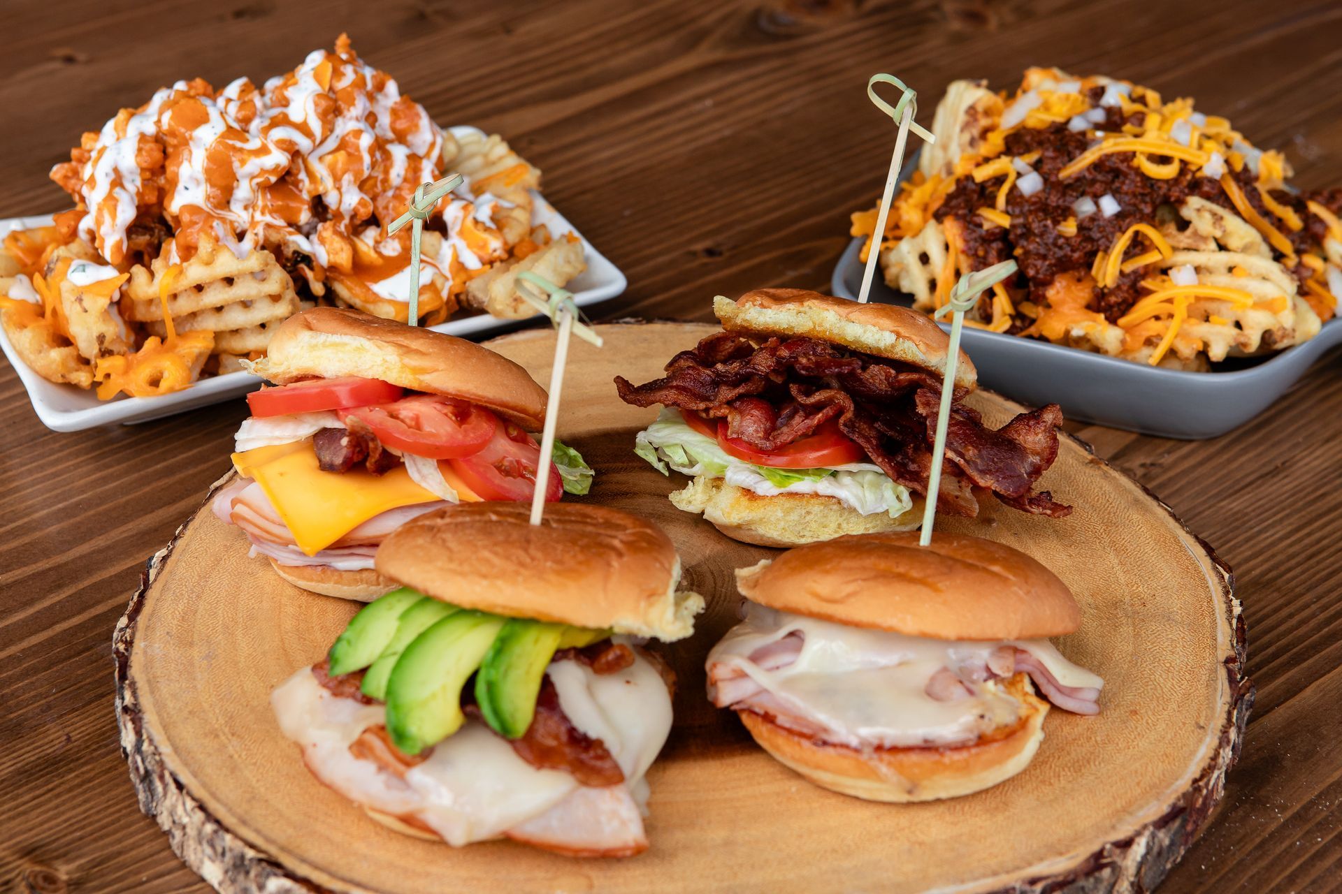 A wooden table topped with a variety of sandwiches and french fries.