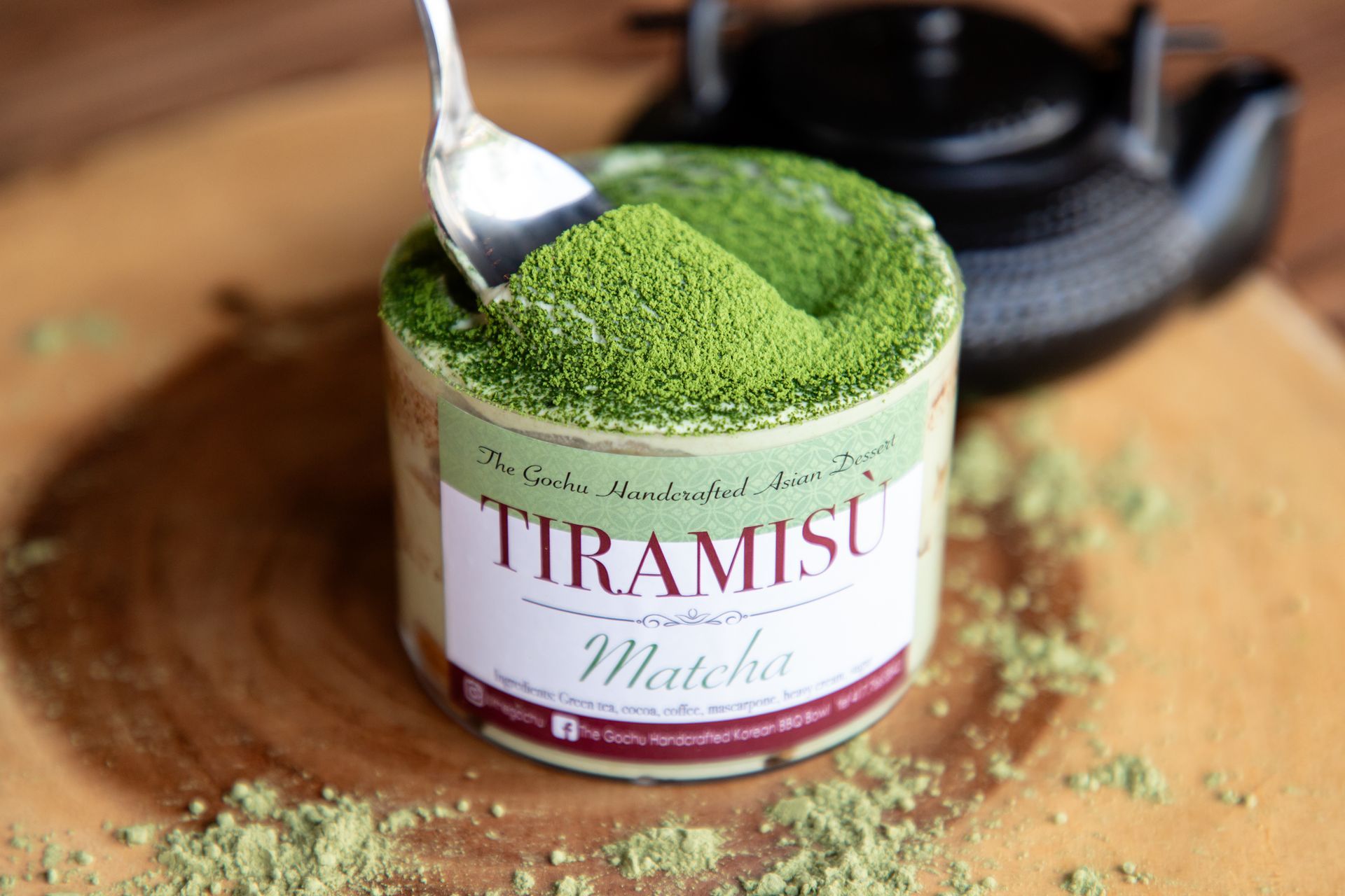 A can of tiramisu with a spoon in it on a wooden table.