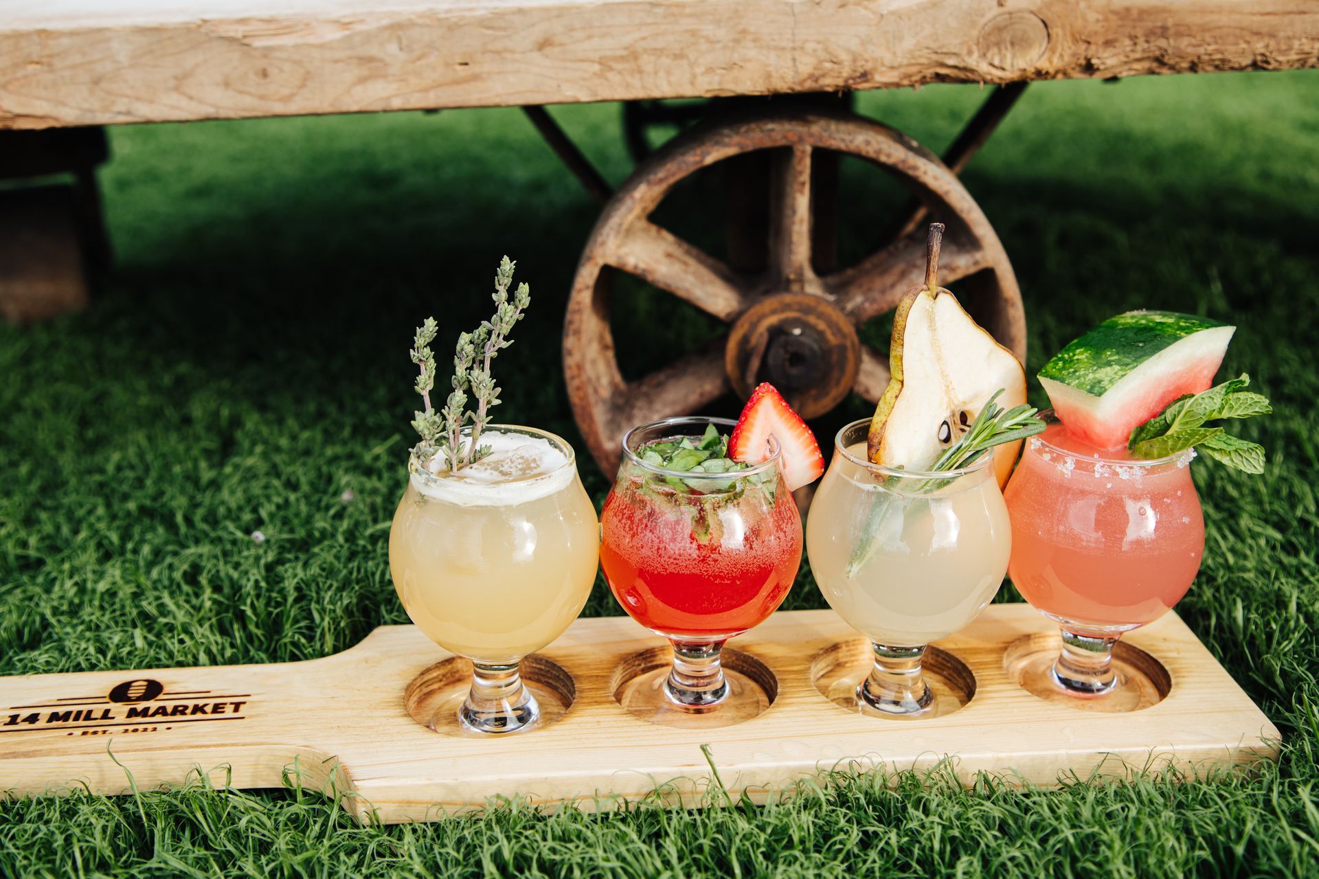 A wooden cutting board with four different types of drinks on it.