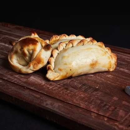 Two pastries are sitting on a wooden cutting board.