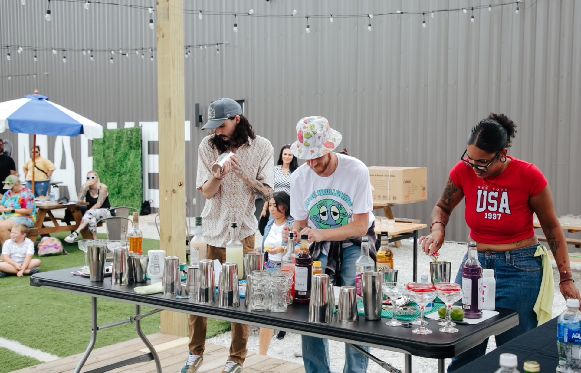 A group of people are standing around a table making drinks.