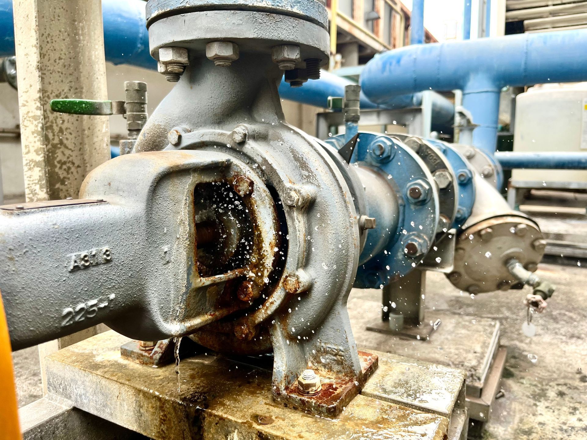 Industrial water pump with a leaking housing connected to large pipes in a facility.