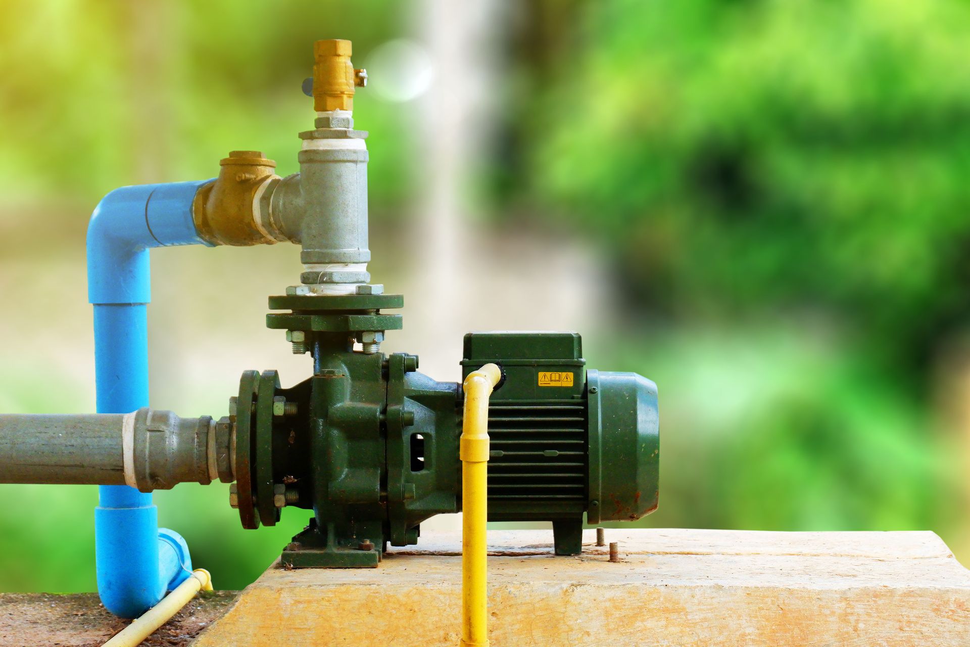 Water pump and motor connected to piping and valves in an outdoor water system installation.