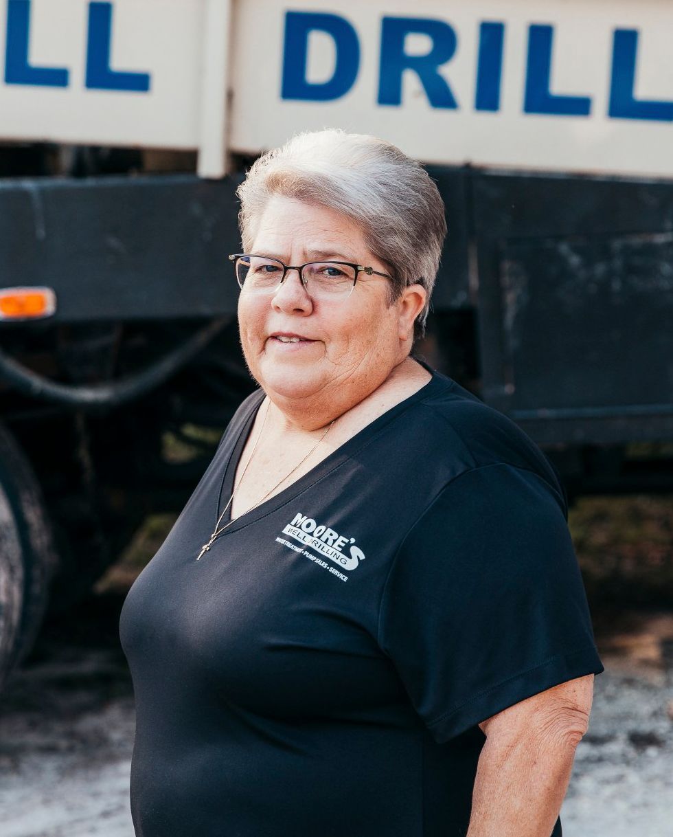 Woman in black shirt with short hair, in front of a truck with