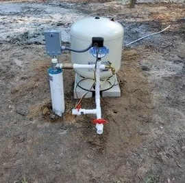 Residential well pressure tank and pump plumbing with control box installed outdoors, the type of sy