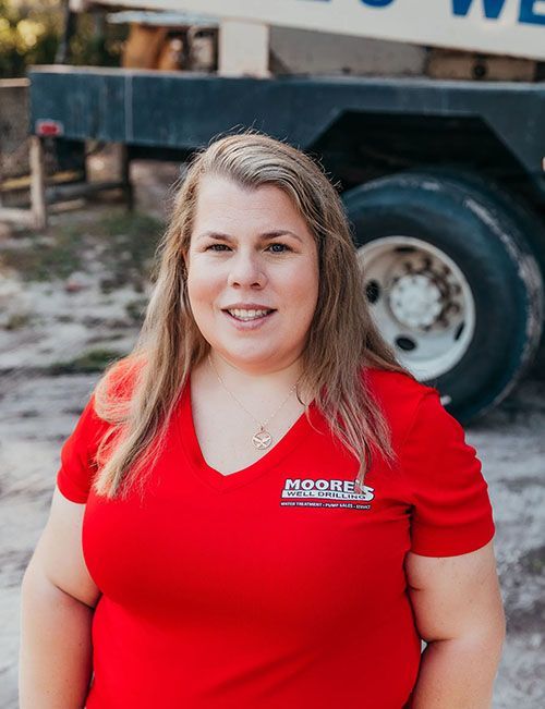 Woman in red shirt smiling in front of a truck.