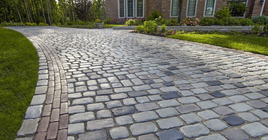 Grey cobbled driveway curving past a lawn with a red brick edge in Sheffield