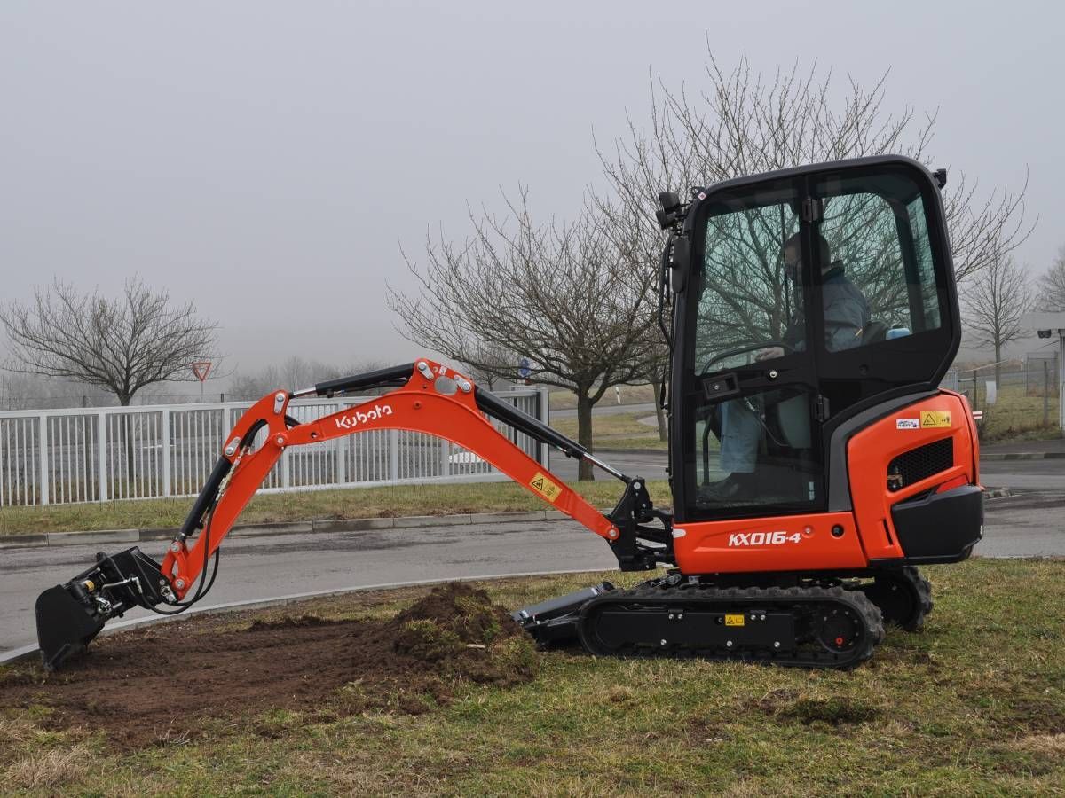Kubota mini digger with a cab digging out a lawn in Sheffield