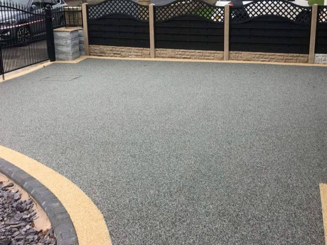 Charcoal resin driveway with a buff resin curve and black fencing
