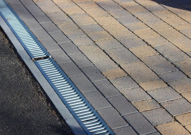 Buff block paving finished against a steel channel drain