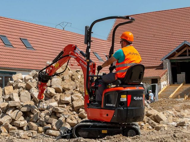 Micro digger and driver moving rubble on a building site in Sheffield