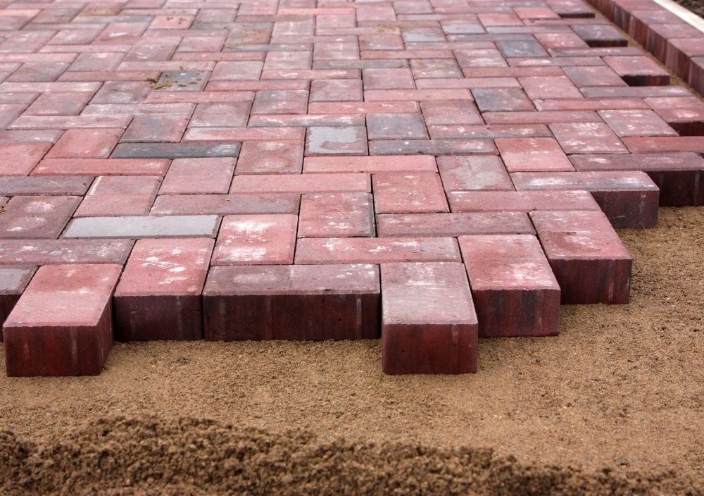 Red block paving part-laid on a levelled sand bed in Sheffield