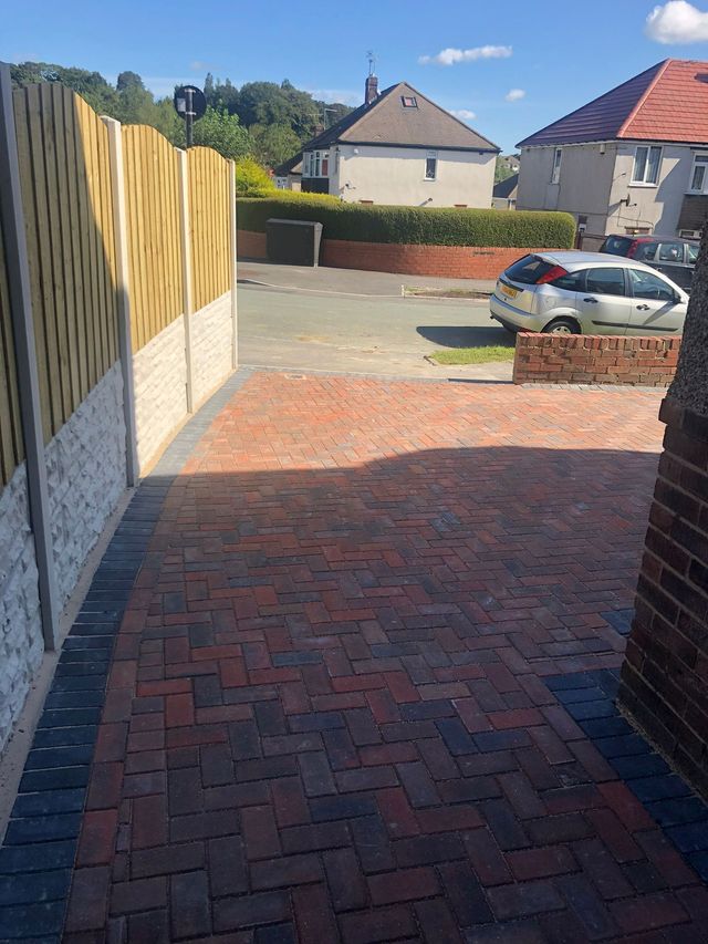 Red block paving driveway with charcoal edging beside a fence in Sheffield