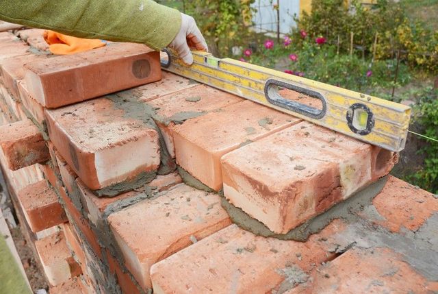 Bricklayer checking a new course of red bricks with a spirit level in Sheffield