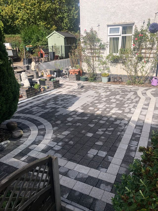 Grey block paving patio with a curved charcoal border pattern